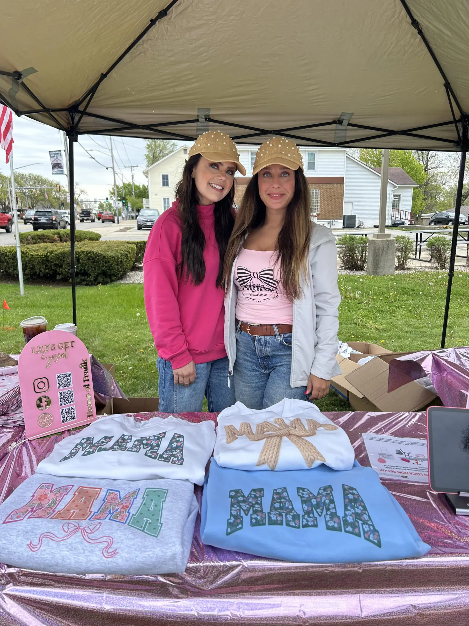 Two women selling shirts at outdoor booth.